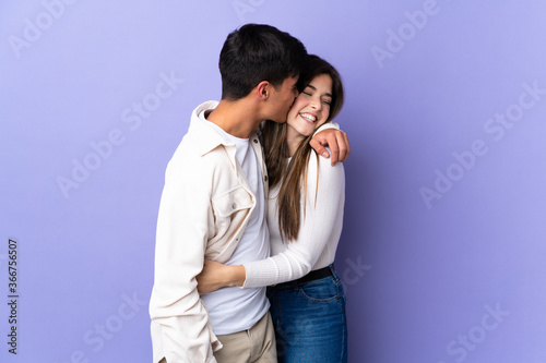 Young couple over isolated purple background kissing