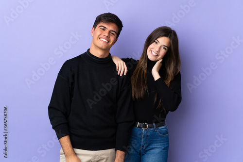 Young couple over isolated purple background happy and laughing