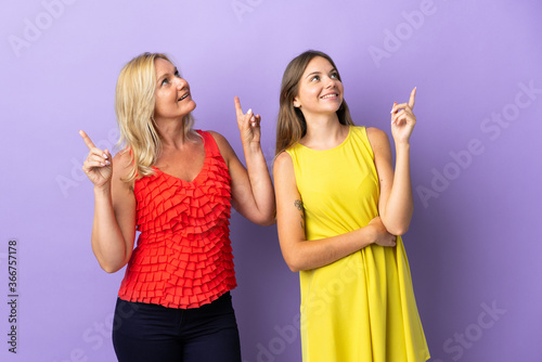 Mom and daughter isolated on purple background pointing with the index finger a great idea