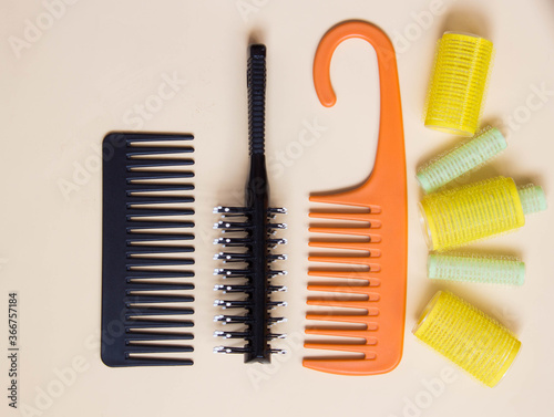Green yellow curlers, combs, hair brush. Hair care concept. Pastel background. Top view