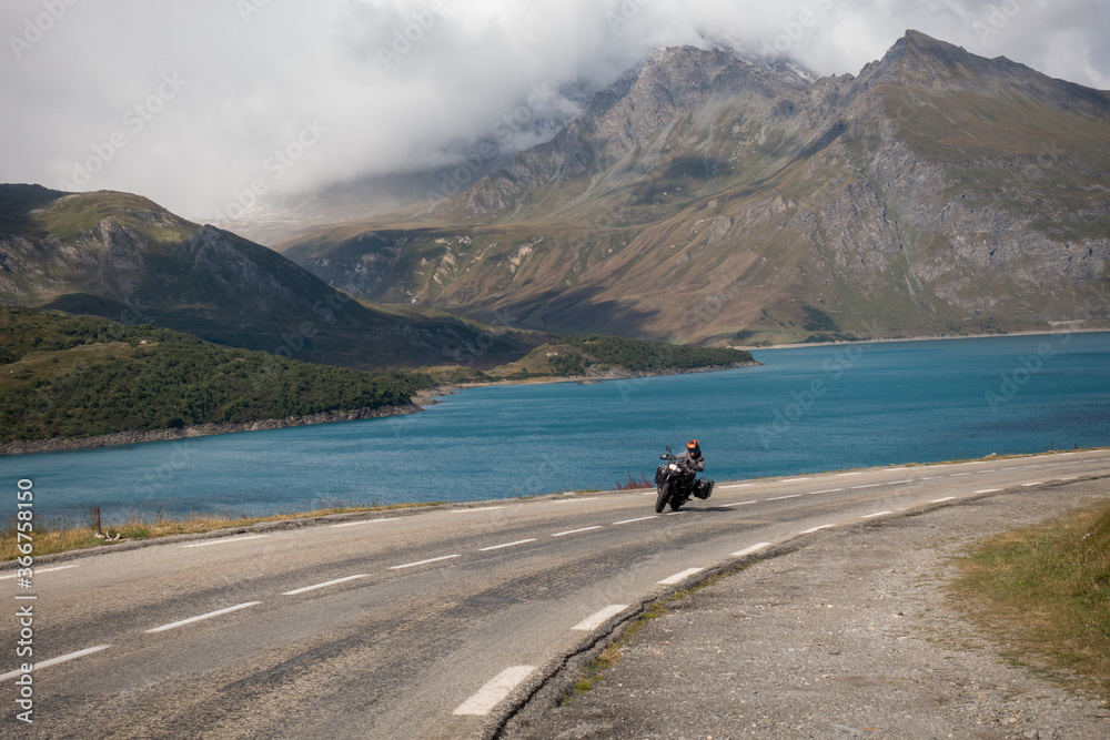 Trail motorcycle rider leading towards a curve in alpine road of Mont Cenis, Italy Trail motorcycle rider leading towards a curve in alpine road of Mont Cenis, Italy