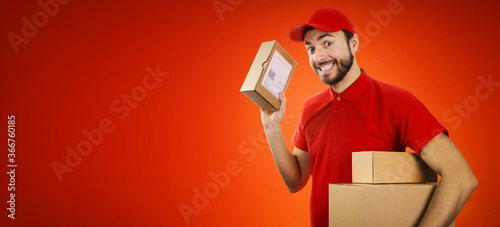 funny delivery service man with box in hand on red background with copy space photo
