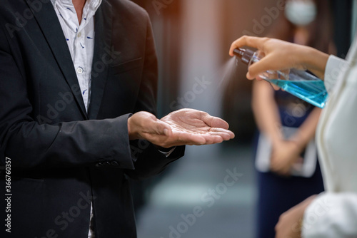 Selective focus alcohol spray on man's hands at workplace before start working for coronavirus protection.