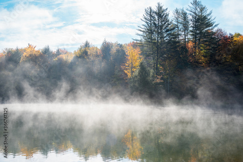 Mountain lake covered in morning fog in autumn