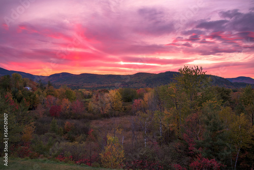 Stunning sunset over forested mountains during the peak of autumn colour season. North Conway, NH, USA.