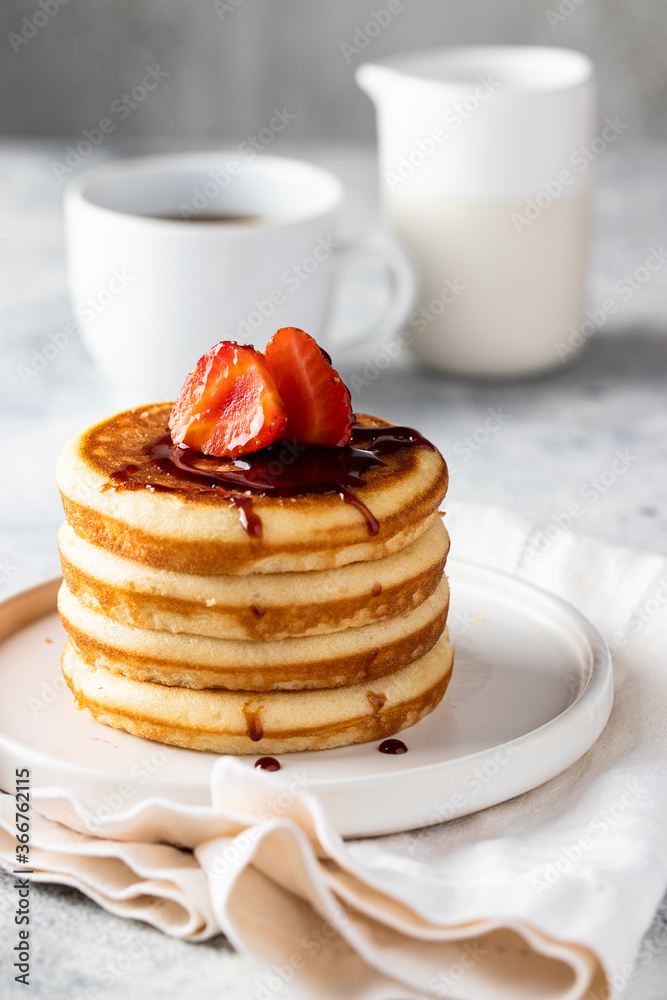 Stack of classic american pancakes with strawberry and sirop . black coffee cup and milk on the white table. Copy space Stack of classic american pancakes with strawberry and sirop . black coffee cup and milk on the white table. Copy space