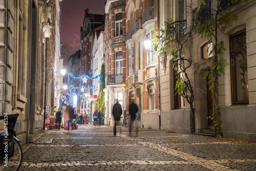 Cobblestone pedestrian street lined with historic buildings in a old city centre at night in winter. Antwerp, Belgium.