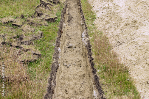 A trench in the ground for laying communications.