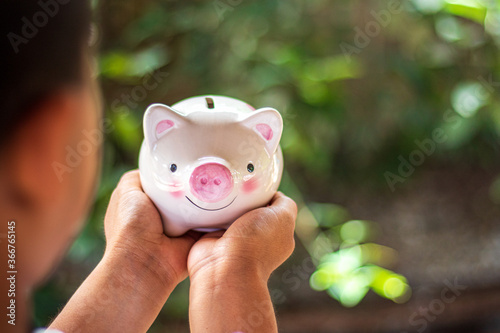 Hand holding piggy bank on nature blurred background.