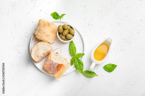Gravy boat of tasty olive oil and bread on white background