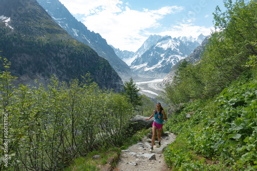 Trail runner woman running with scenic view Mer du Glace Glacier in Mont Blanc Mountain Ridge in Chamonix, France
