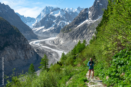 Trail runner woman running with scenic view Mer du Glace Glacier in Mont Blanc Mountain Ridge in Chamonix, France