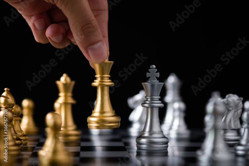 Hand holding and move golden king chess to silver chess.