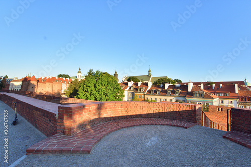 The historic defensive walls of the Warsaw Barbican and burgher houses in the Old Town in the light of the rising sun.