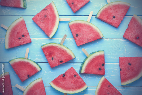 Top view, flat lay watermelon slice popsicles on a blue old wooden background.