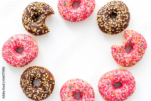 Frame of donuts with icing and sprinkles, overhead view. Colorful bakery
