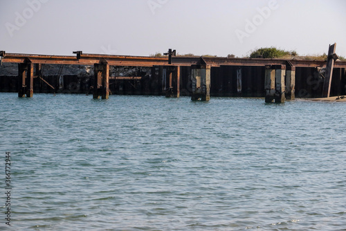 Old rusting metal and concrete pier in clear blue Mediterranean water near Famagusta, Cyprus.