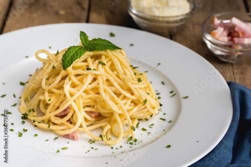 Spaghetti a la carbonara on a white plate and rustic table