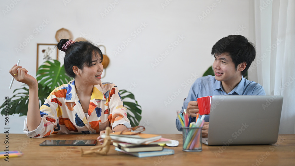 The graphic design team is working with a computer laptop at the wooden table. The graphic design team is working with a computer laptop at the wooden table.