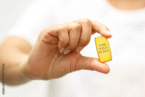 Woman hand holding a gold bar to take a close up photo