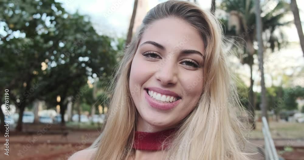Pretty smiling joyfully female, looking with satisfaction at camera, being happy. Outdoor shot of good-looking beautiful woman in a park. 4K. Pretty smiling joyfully female, looking with satisfaction at camera, being happy. Outdoor shot of good-looking beautiful woman in a park. 4K.