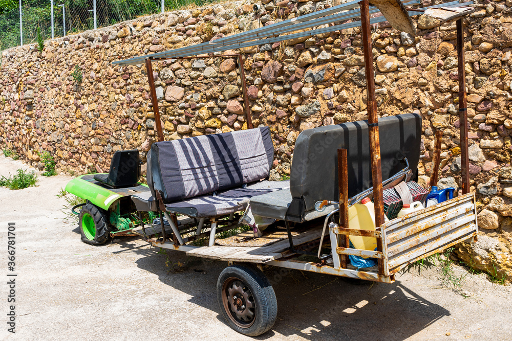 Fototapeta premium Old green tractor adapted with a trailer to carry passengers and garden tools