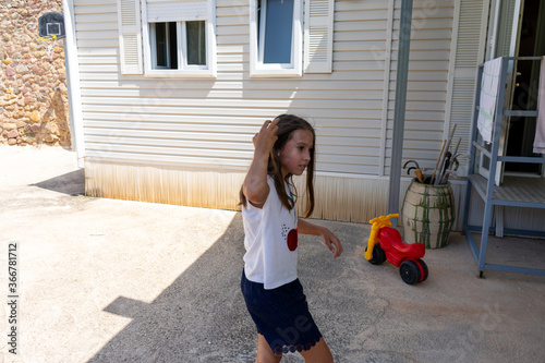 Pretty little girl in a white shirt and blue skirt posing fun in a house surrounded by greenery in the rural town of Ayodar photo