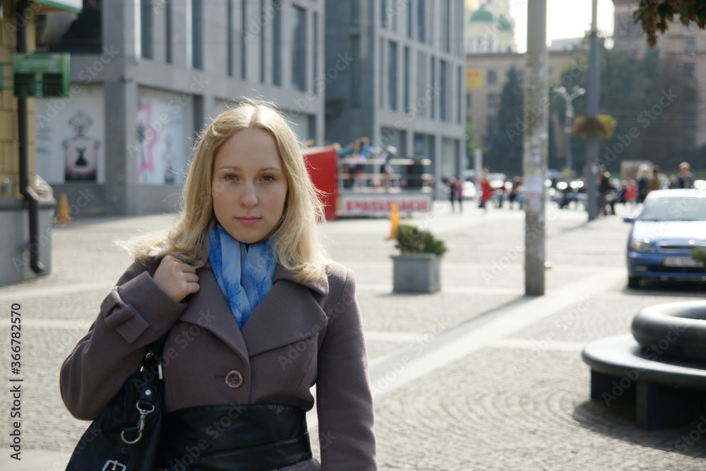 Beautiful blonde girl in the city. Sunny day. Business woman