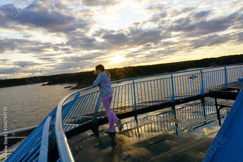 Young girl on a ferry between Stocholm and Turku. Sunset and beatiful sky.