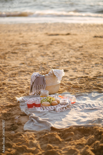 Beautiful romantic summer picnic on a beach at sunset with fresh fruits and drinks.