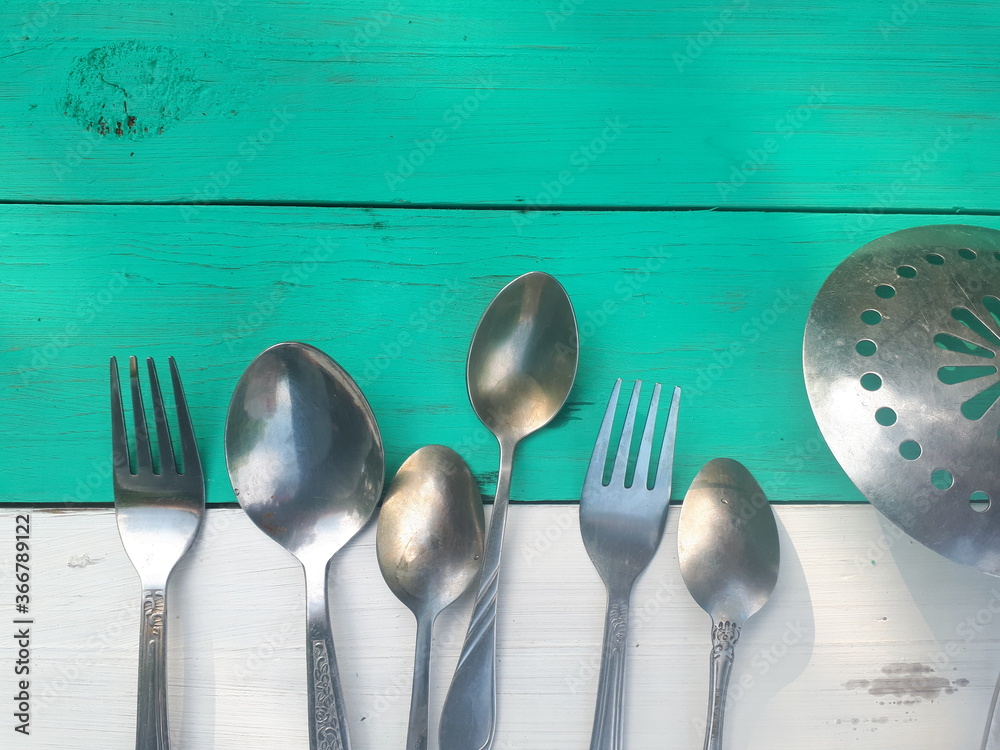 Cutlery on a wooden surface. The background is white and green.