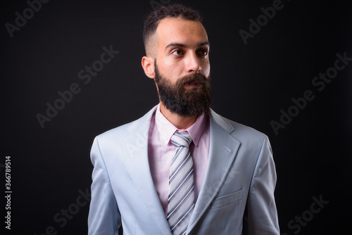 Young handsome Persian businessman with dreadlocks against black background © Ranta Images