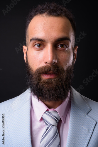 Young handsome Persian businessman with dreadlocks against black background