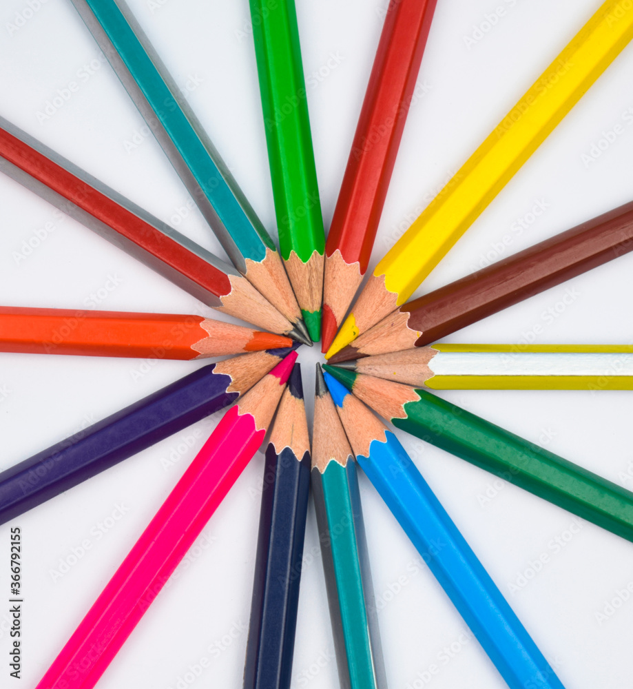Various color wood pencil crayons placed as a round circle on white paper
