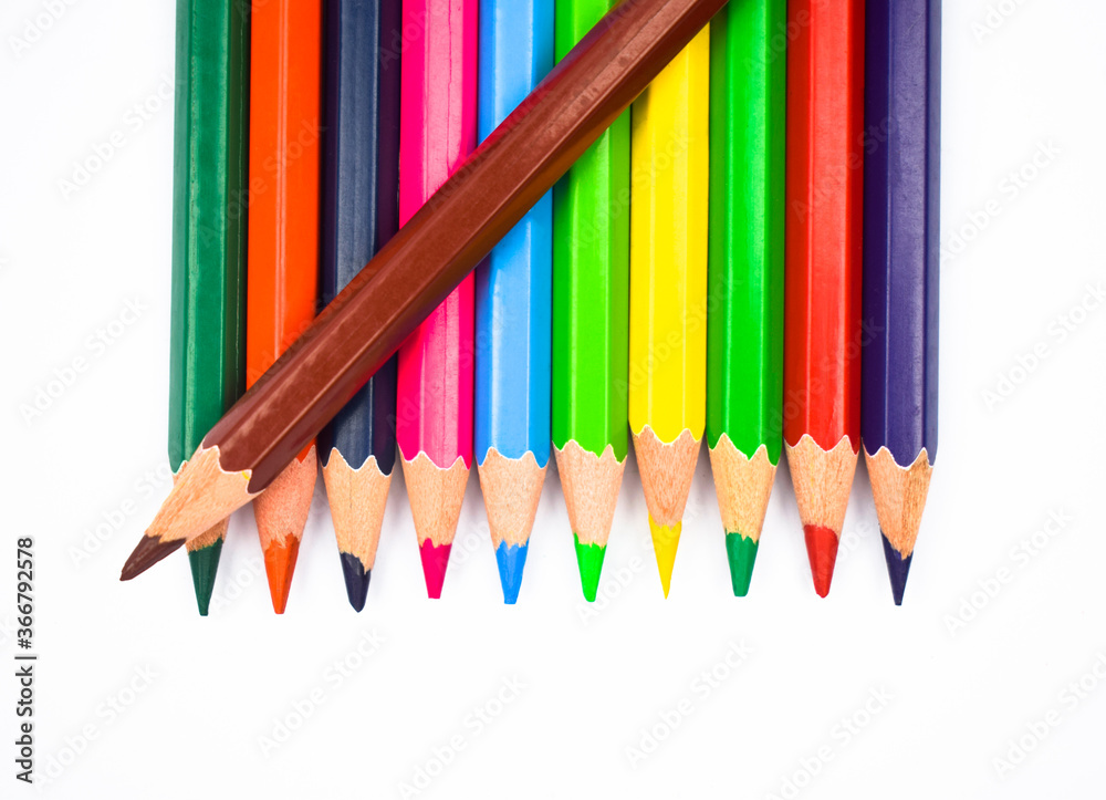 Brown color wood pencil crayon placed on top of a row of different color wood pencil Brown color wood pencil crayon placed on top of a row of different color wood pencil