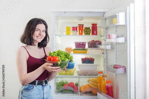 smile girl with vegetables near refrigerator with healthy food