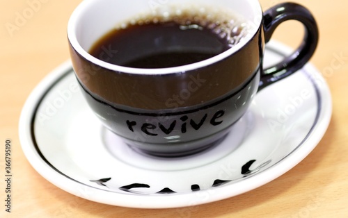 Black coffee cup with a white saucer with black writing,
