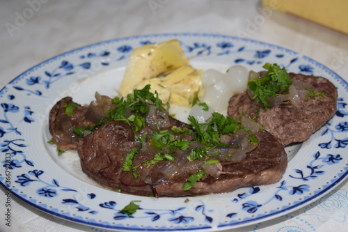 Roast beef heart with parsley and onions, served in a white and blue dish