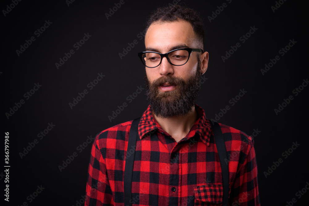 Young handsome Persian man with dreadlocks against black background