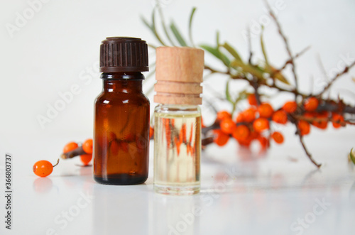 sea-buckthorn berries cluster and oil bottle jar isolated on a white background