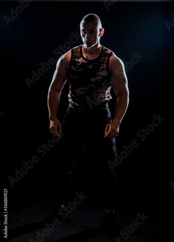Man posing and showing his arm muscles while posing on black background