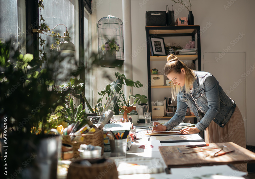 Young artist working in art workshop. Concept of small creative business. Concept of freelance work. Happy woman painting in art studio. Young artist working in art workshop. Concept of small creative business. Concept of freelance work. Happy woman painting in art studio.