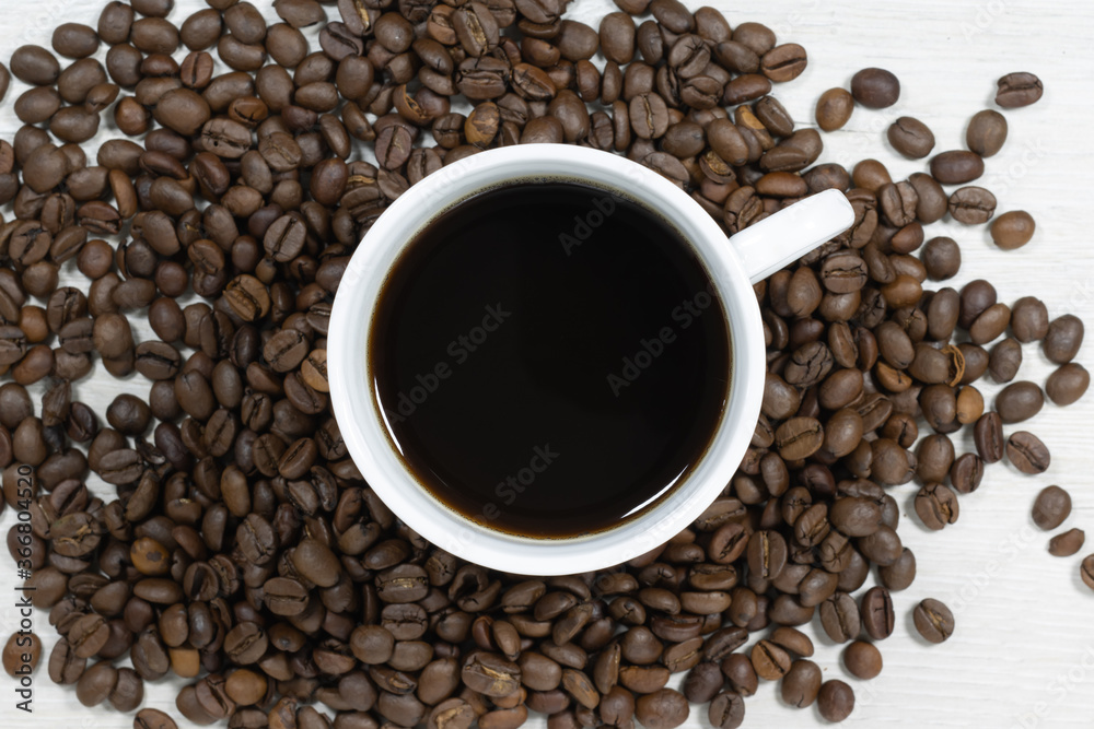 Grains of coffee with a cup of coffee on a background of bleached wood. Grains of coffee with a cup of coffee on a background of bleached wood.