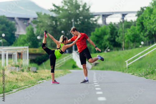Young couple warming up and stretching together in a park before running