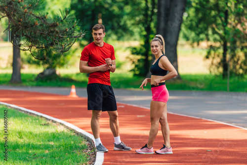 Beautiful fitness couple taking a rest after fast running in the park