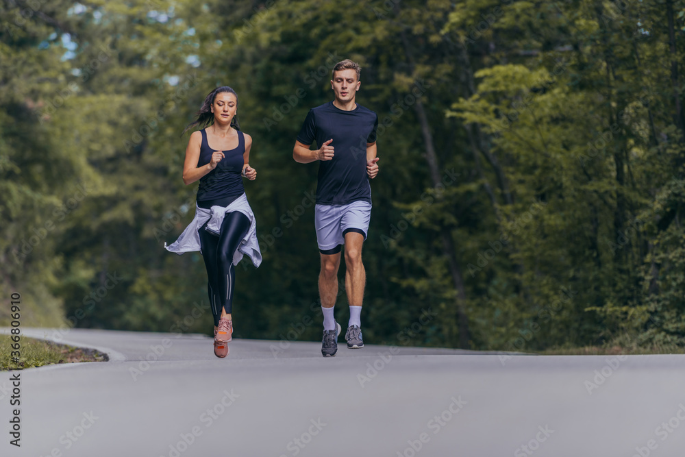Athletic couple running on a street next to each other. Nature,fit and healthy concept. Athletic couple running on a street next to each other. Nature,fit and healthy concept.