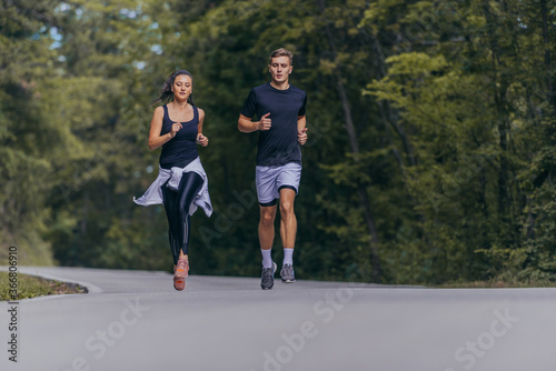 Athletic couple running on a street next to each other. Nature,fit and healthy concept.