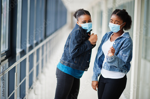 Two african woman friends in jeans jacket wearing protective masks. Virus concept health, medical.