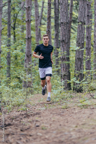 Fototapeta Naklejka Na Ścianę i Meble -  Full-length picture of an attractive male athlete running in the woods