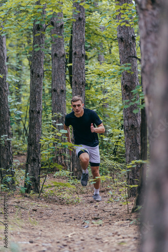 Full-length picture of an attractive male athlete running in the woods